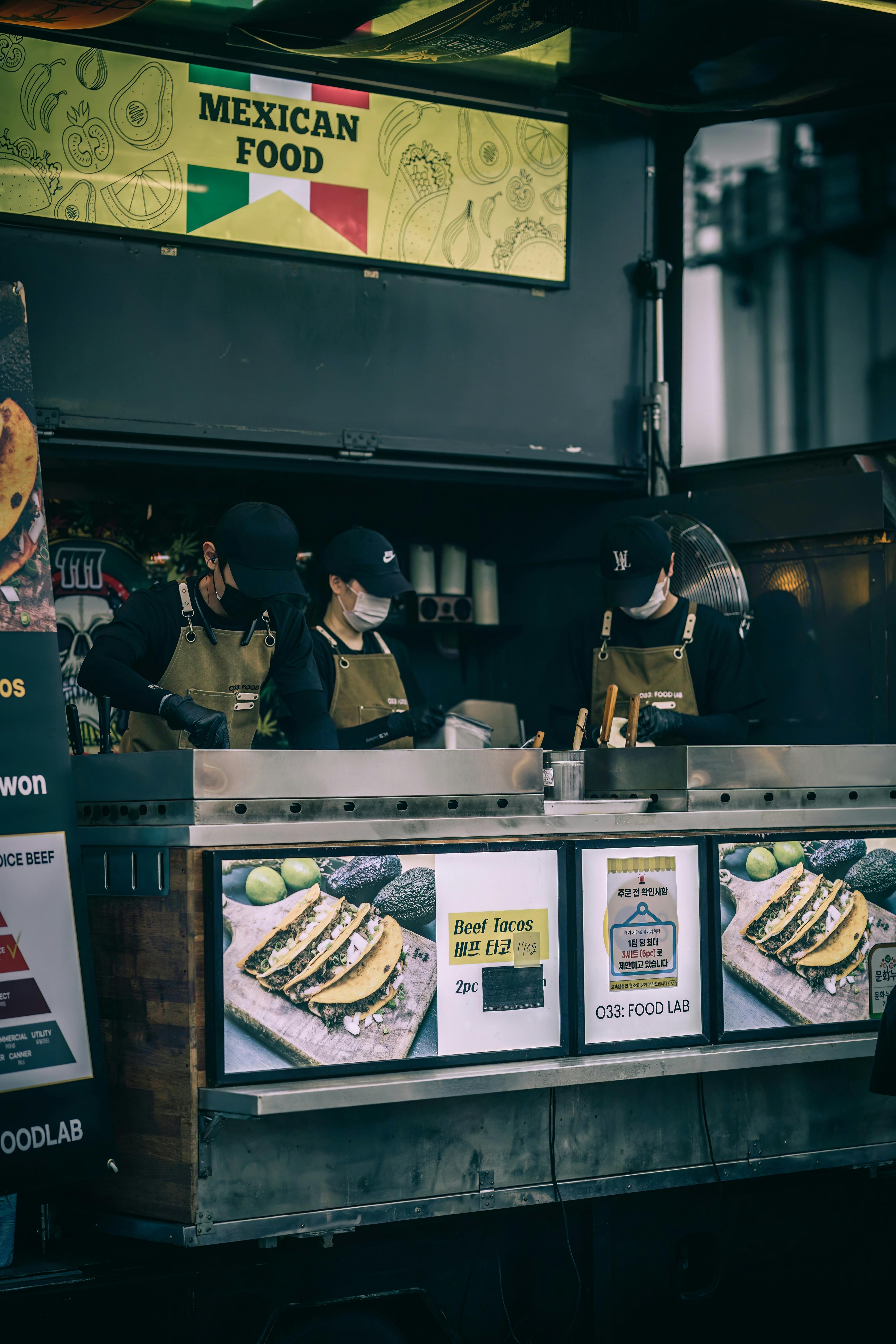 Street vendors cooking Mexican food at an urban food stall, showcasing delicious tacos.