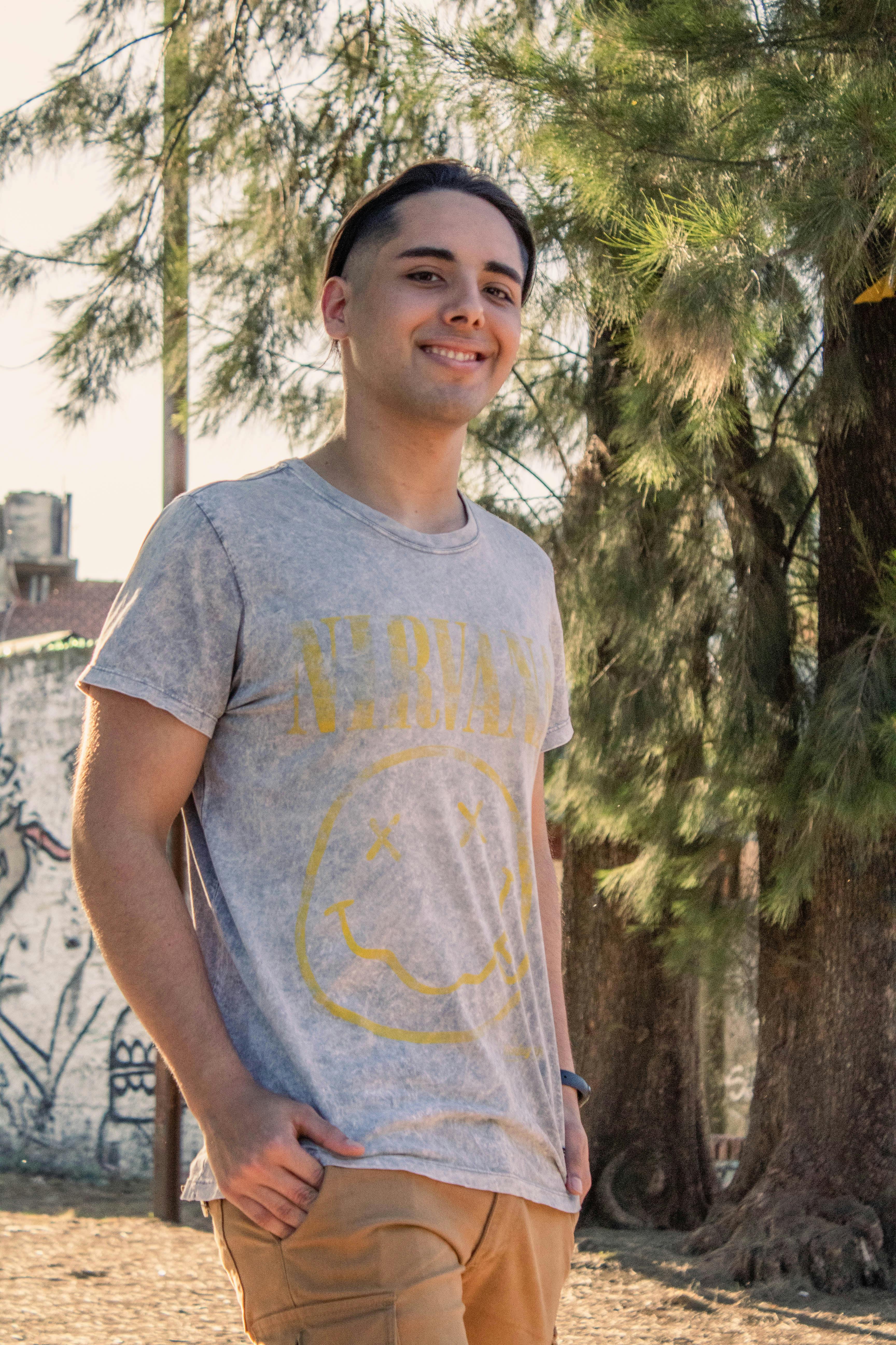 Smiling young adult standing in a park, enjoying a sunny day outdoors.