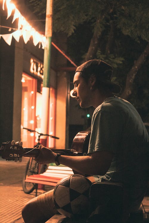 Man Sitting on a Street at Night 