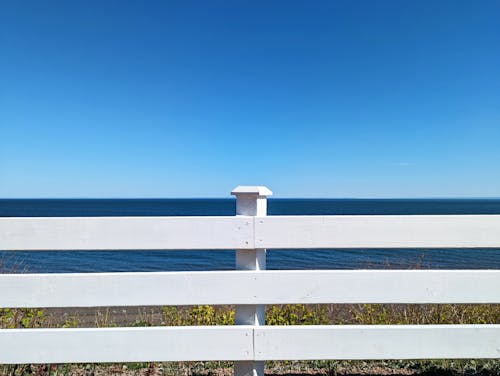 A White Fence on the Background of a Sea and Blue Sky 