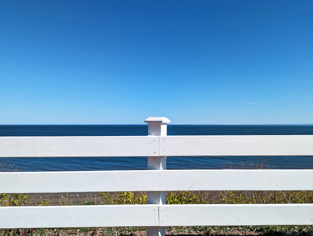 A White Fence on the Background of a Sea and Blue Sky 