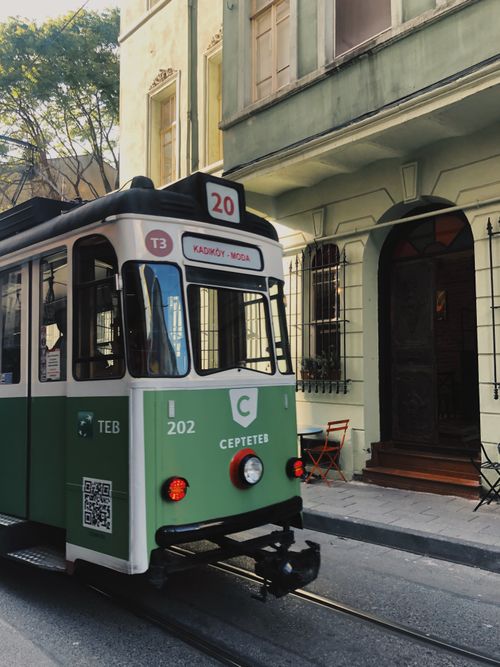 Free A vintage green tram navigating a narrow urban street beside historic buildings. Stock Photo