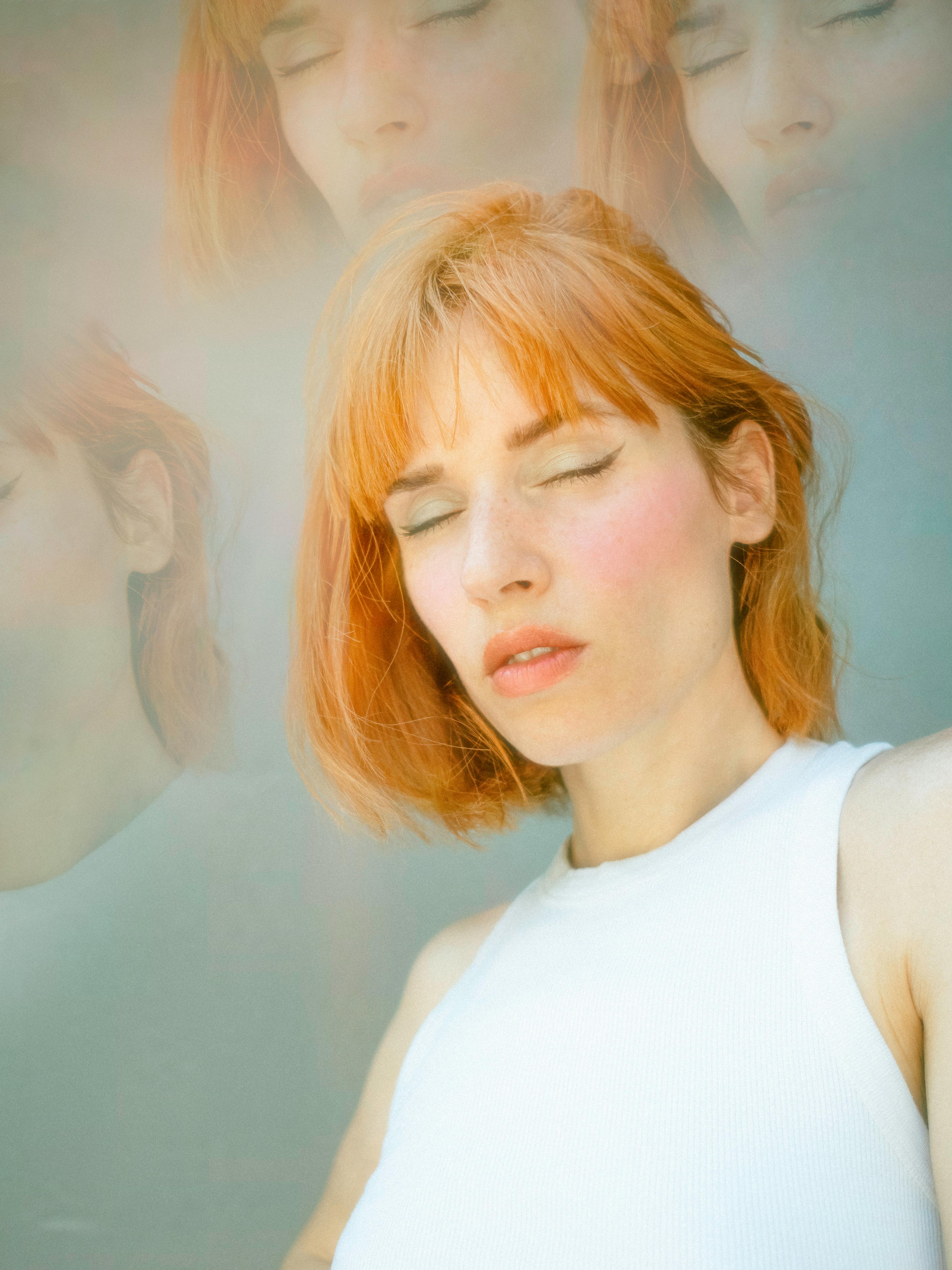 A dreamy artistic portrait of a redhead woman with eyes closed, featuring a soft overlay effect.