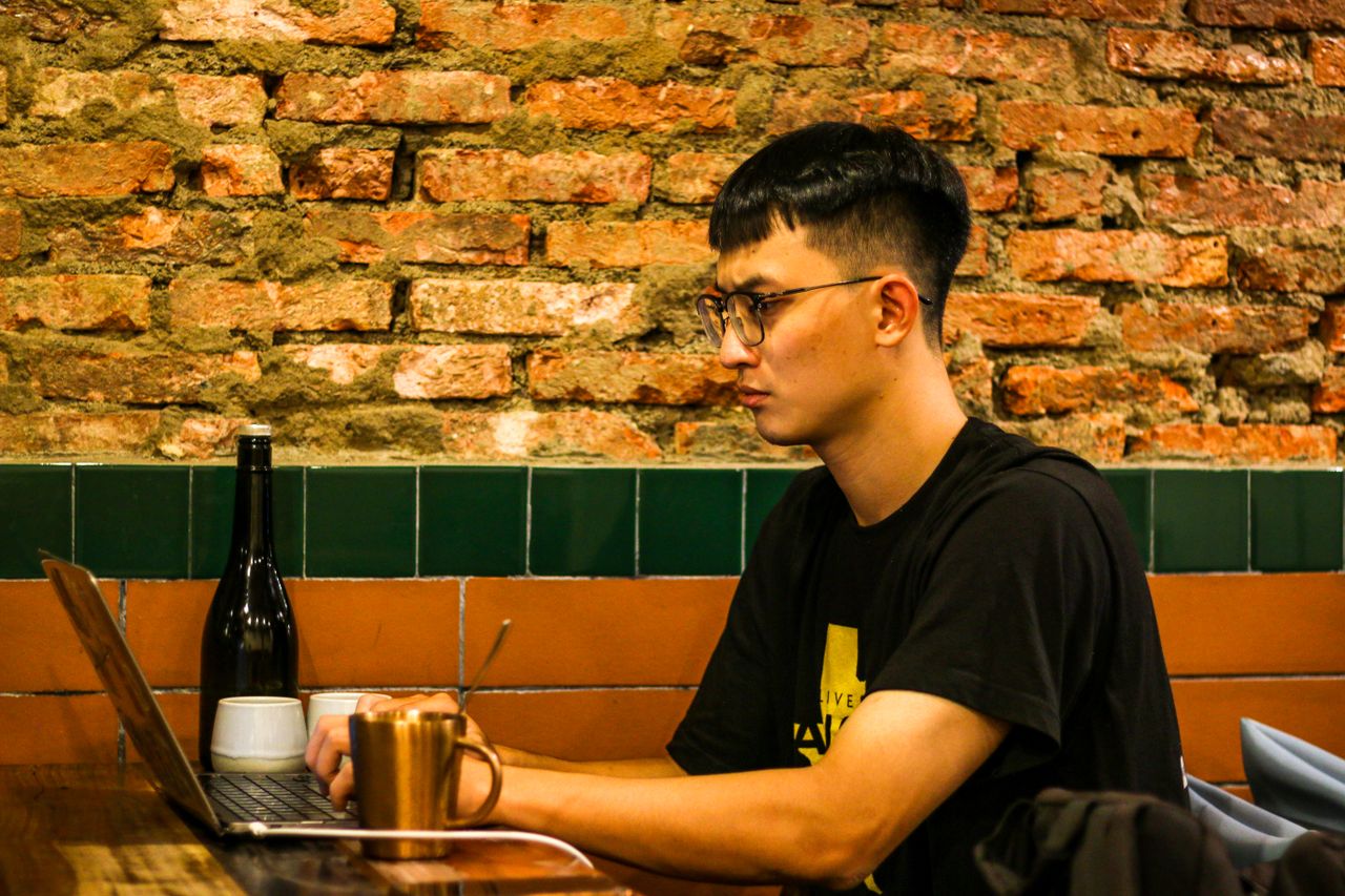 Ilustrasi mahasiswa belajar dengan laptop di kafe dengan dinding bata ekspos