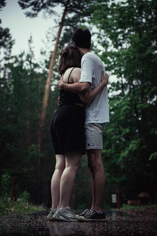 Free A couple embraces on a forest path during rain, capturing a moment of love and tranquility. Stock Photo