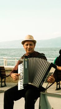 A cheerful musician plays the accordion on a seaside pier, creating a lively atmosphere.