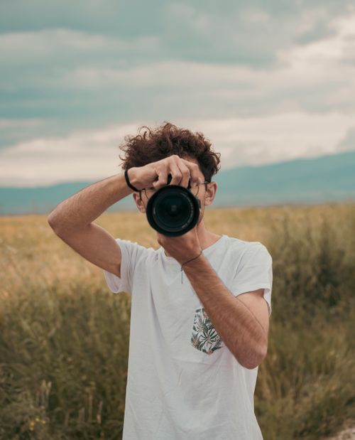 Free A photographer in a white shirt taking pictures in a rural field, capturing the essence of nature. Stock Photo