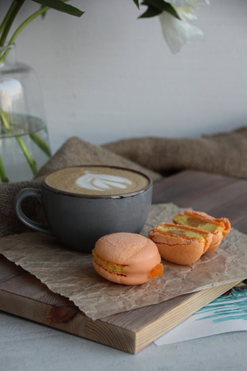 Cuo of Cappuccino and Orange Macaroons on Cutting Board