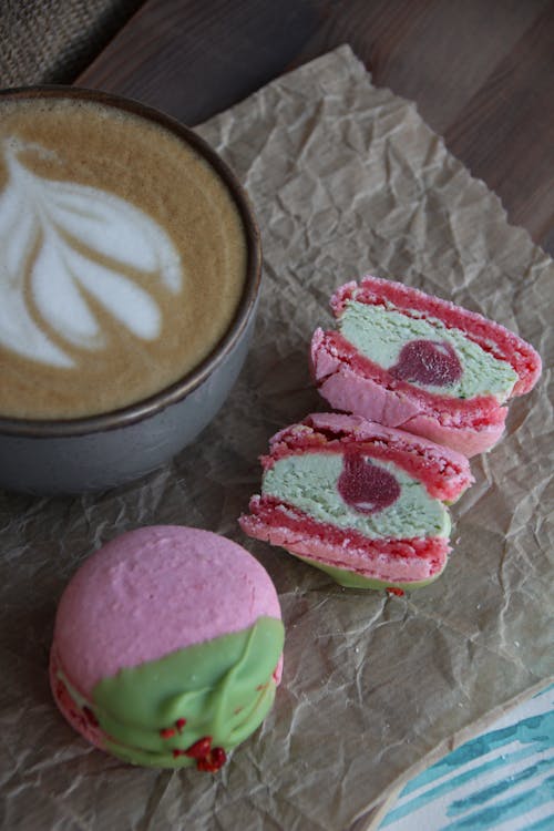 Cup of Cappuccino Cup and Pink and Green Macaron Pastry Cut in Half