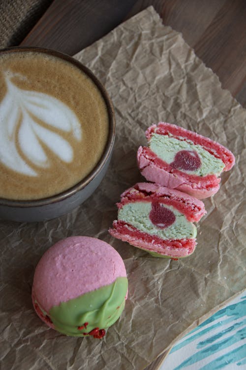 Free Cup of Hot Cappuccino with Delicious Pink and Green Macaron Cookies Stock Photo