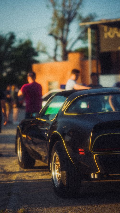Free Rear view of a classic black car at an outdoor event with people in the background. Stock Photo