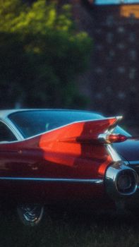 Beautiful red vintage car showcasing its iconic tailfin design at sunset.