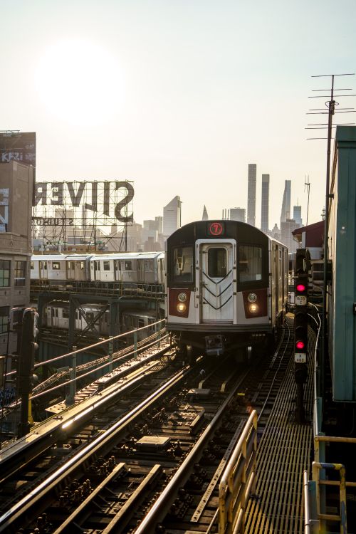 Free Elevated subway train in New York City with skyline and sunlight in the background. Stock Photo