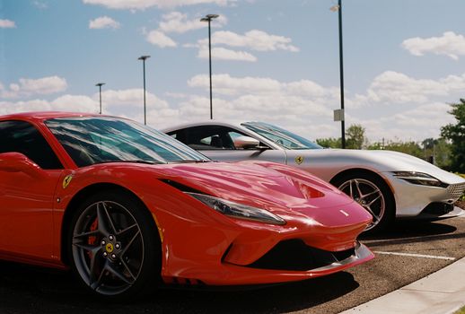 Red and white luxury sports cars parked on asphalt under a bright blue sky in St. Louis.