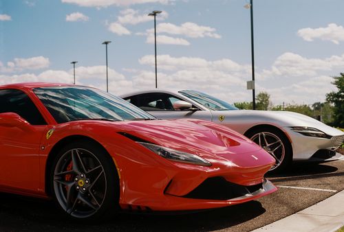 Free Red and white luxury sports cars parked on asphalt under a bright blue sky in St. Louis. Stock Photo
