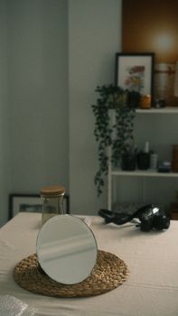 A tranquil minimalist interior featuring a round mirror, glass container, and greenery for a modern aesthetic.