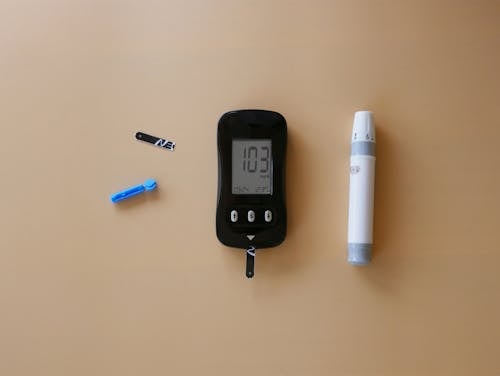 A blood glucose meter and a pen on a table