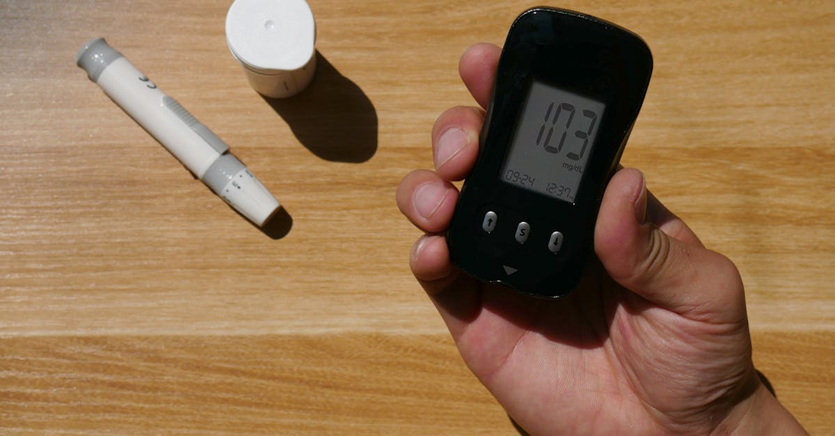 A person holding a blood glucose meter on a table