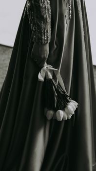 A woman in an elegant evening dress holds a bouquet of tulips, capturing the essence of fashion photography.