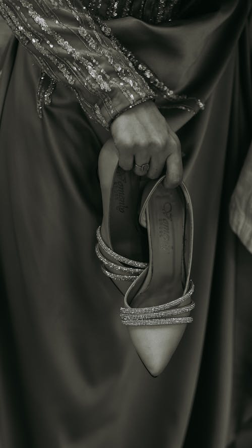 Woman in Gown Holding Heels in Hands
