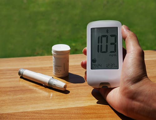 A person holding a blood glucose meter on a table