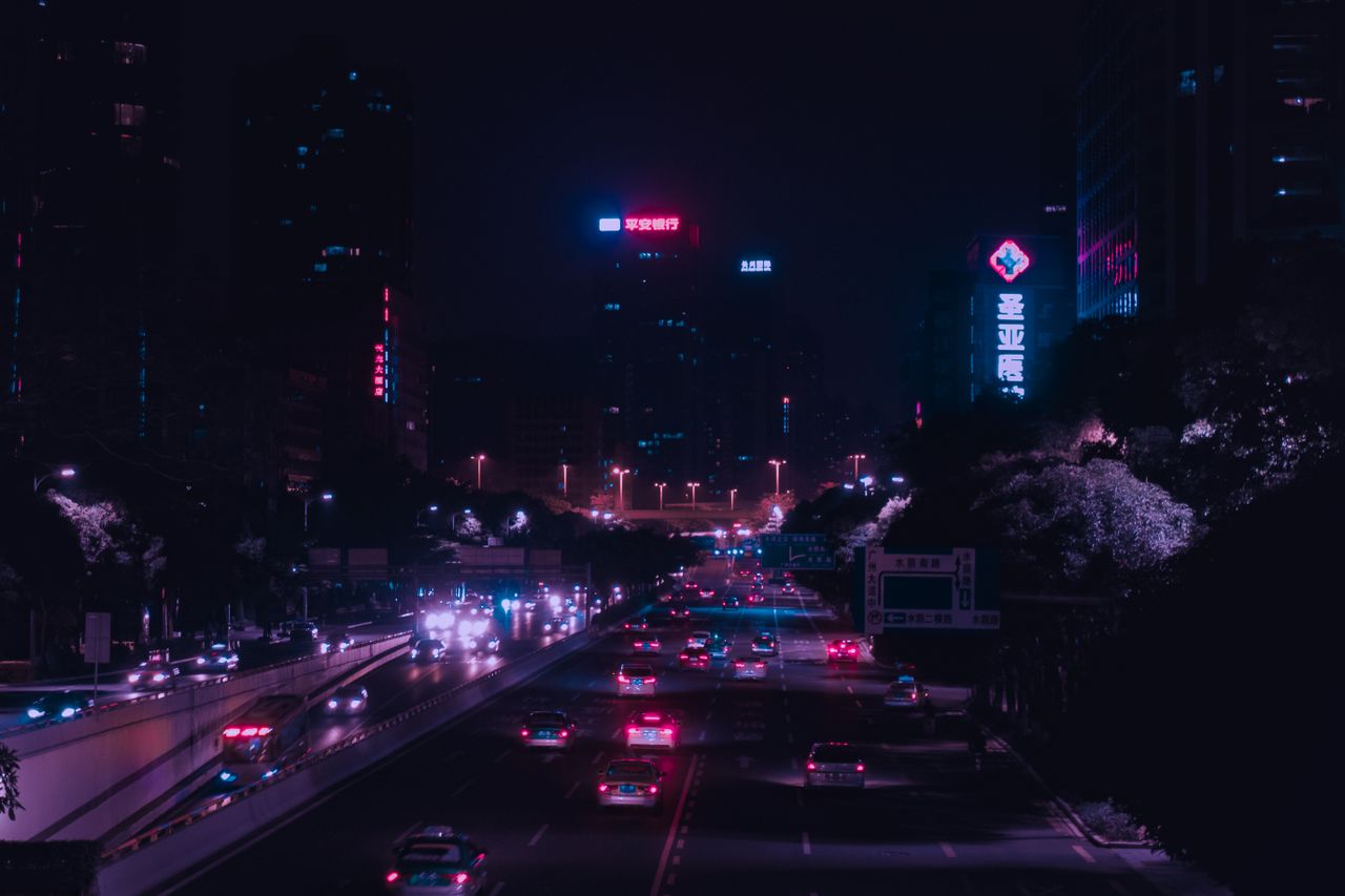 illuminated city street with vibrant lights and traffic in downtown gu