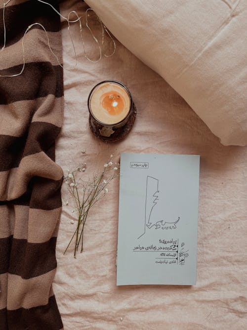 White Flowers by Candle and Book on Bed