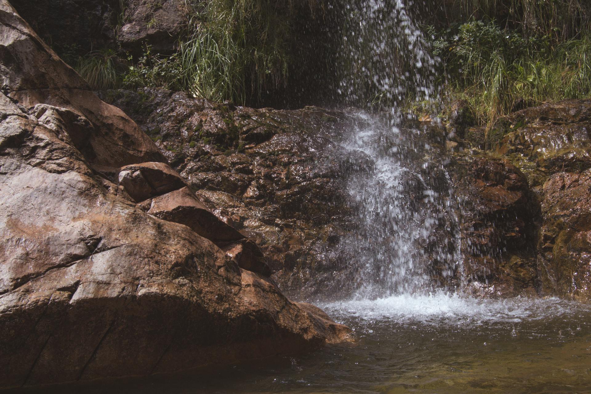 Drops of Waterfall Falling on Rock into Pond