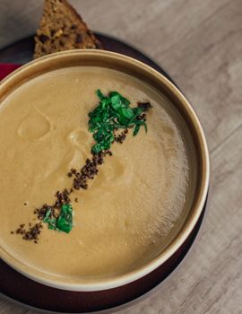 Delicious creamy soup garnished with herbs, served with rustic bread, perfect for a cozy meal.