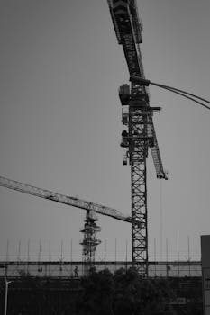 Cranes towering over a city construction site captured in black and white.