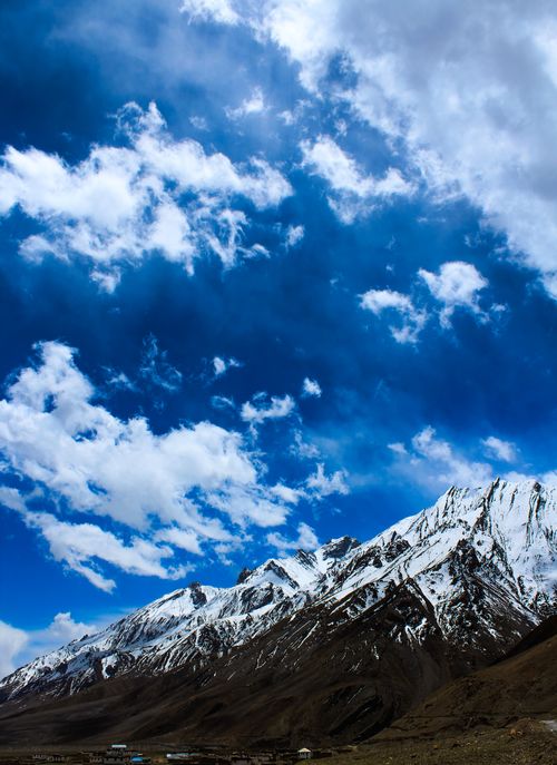Free Captivating snow-covered mountains with a vivid blue sky and scattered clouds, offering a scenic view. Stock Photo