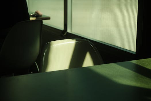 Sunlit interior with shadows on chairs and table by a window.