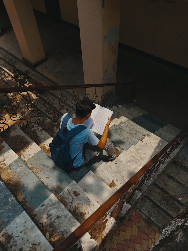 Top View Of A Student Reading On The Stairs