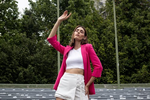 Woman in Pink Shirt Standing with Arm Raised