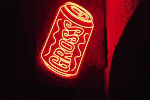 Illuminated red neon sign of a soda can with text 'GROSS' in Valletta, Malta.