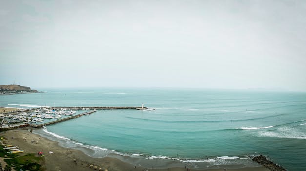Expansive view of a marina nestled on a coastal bay alongside a lighthouse.