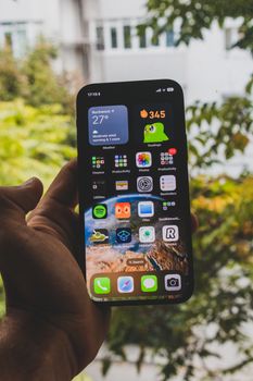Close-up of a hand holding a modern smartphone showing various apps.