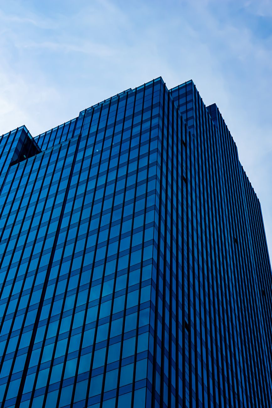 A modern skyscraper with reflective glass facade against a blue sky, showcasing urban architecture.