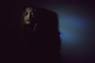 一幅女性艺术肖像，在幽暗而阴郁的灯光下，形成了强烈的阴影