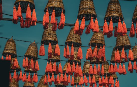 Colorful woven baskets with red tassels hanging in the vibrant streets of Istanbul.