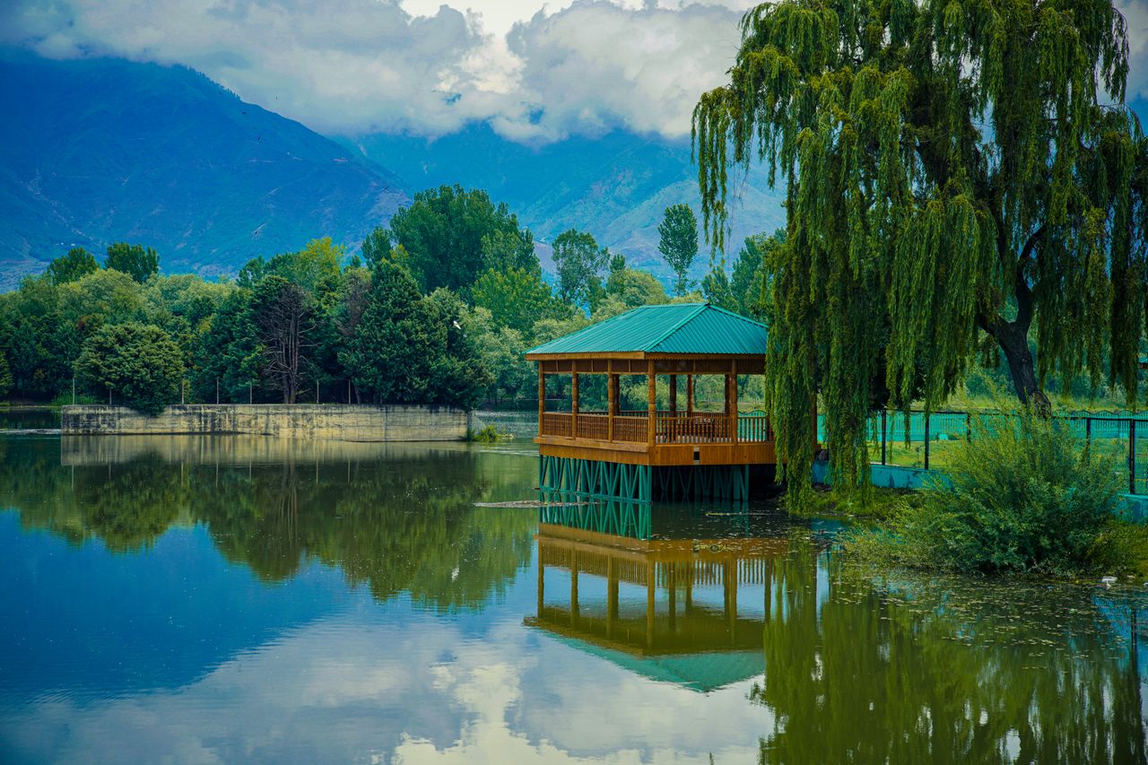 beautiful gazebo by a serene pond surrounded by lush trees reflecting