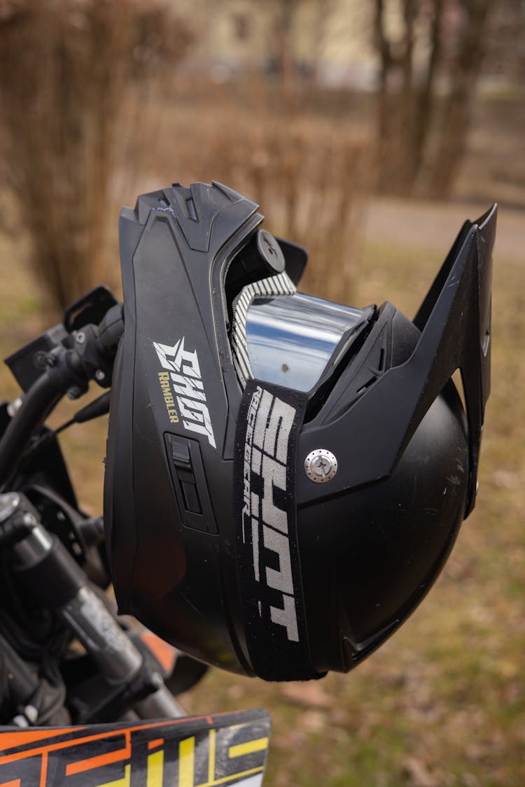 Black Protective Helmet Hanging On A Motorcycle Handlebar