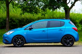 Blue compact hatchback parked on a tree-lined road — photo by Mike Bird on Pexels