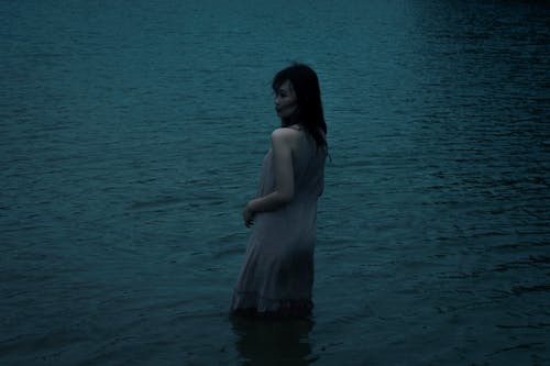 Woman in Violet Dress Standing in Water