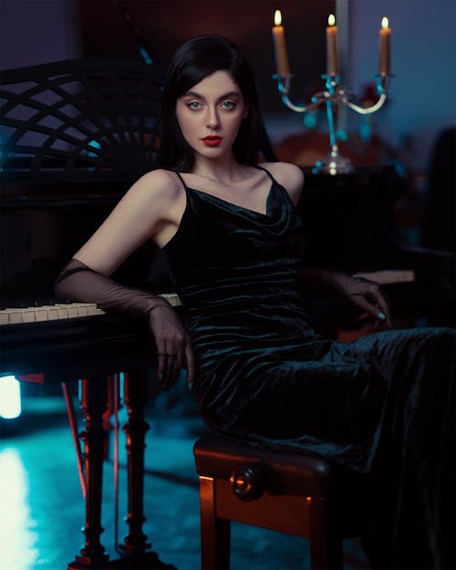 Young Woman in an Evening Dress Sitting and Leaning against a Piano 