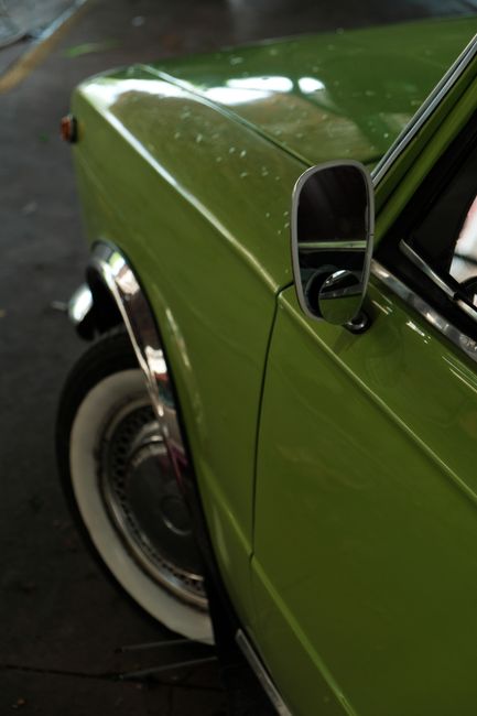 Close-up of a classic green car showcasing vintage design and timeless elegance.