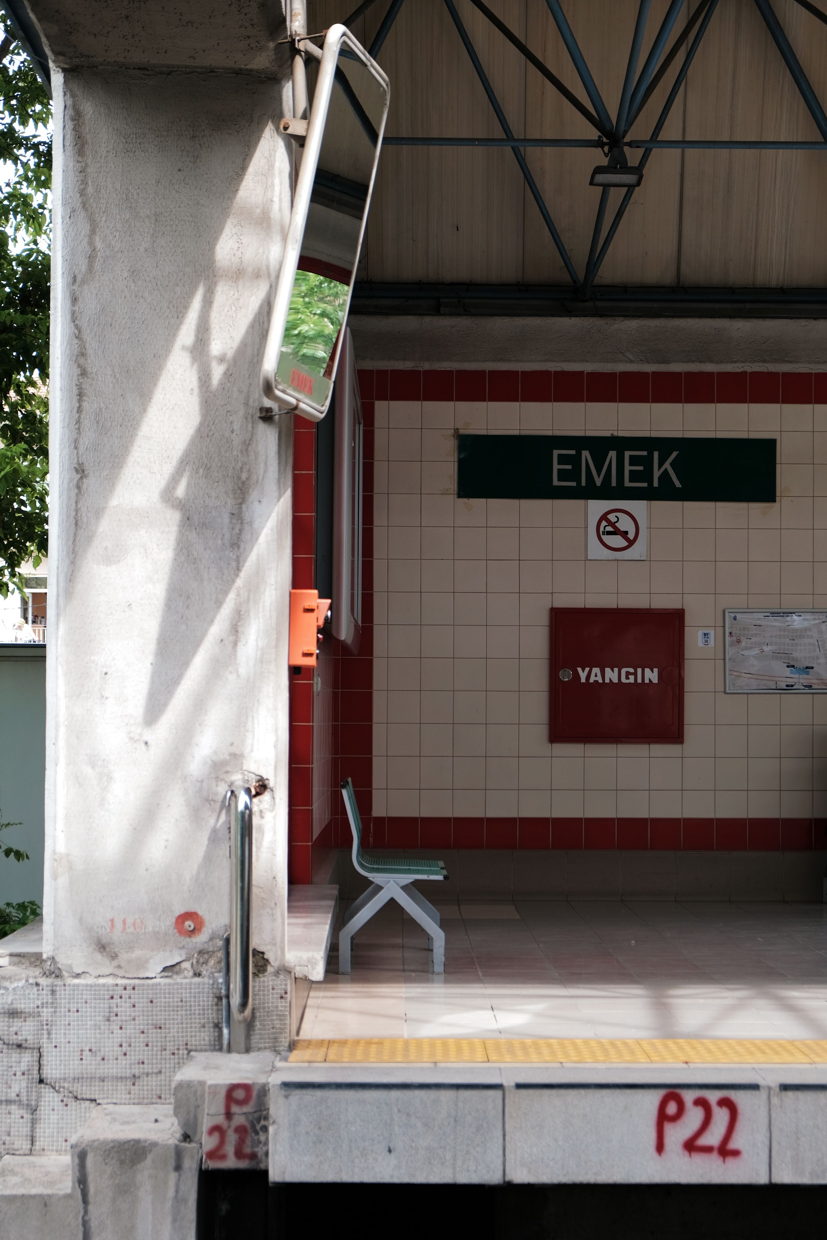 Empty railway station platform featuring Emek signage, mirror, and bench.