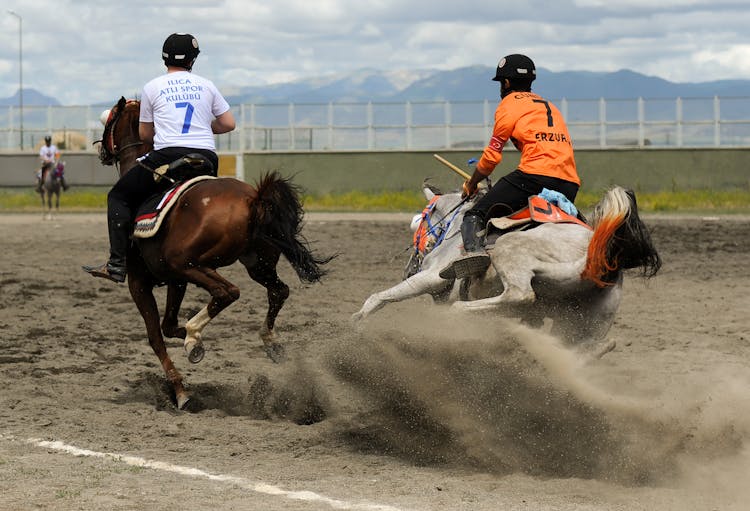 Two Men In Protective Helmets Racing At A Jareed Competition