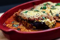 红色托盘上放着美味的烤茄子帕尔马干酪，配以奶酪和番茄酱