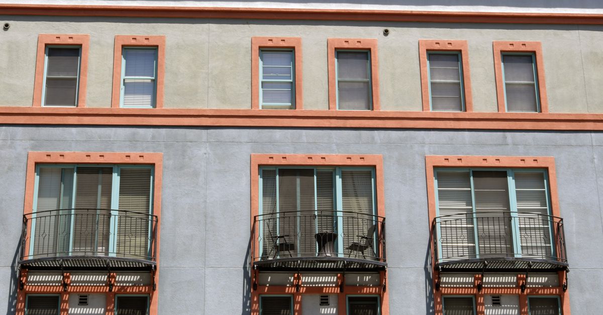 A sunlit urban building facade with multiple balconies and windows in San Jose, CA.